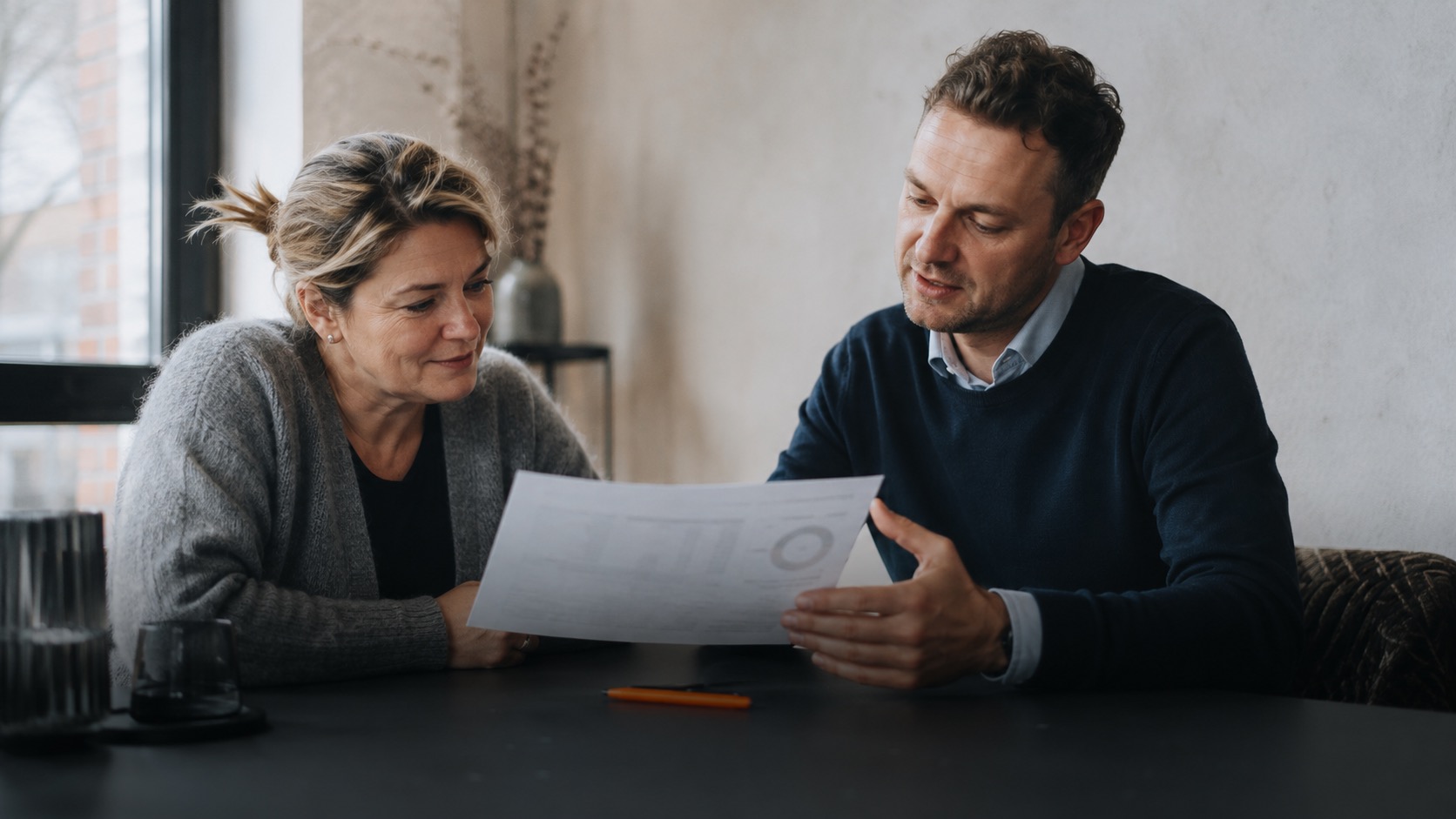 Ein Mann und eine Frau besprechen Unterlagen zur professionellen Verwaltung einer Ferienimmobilie durch Favorent.
